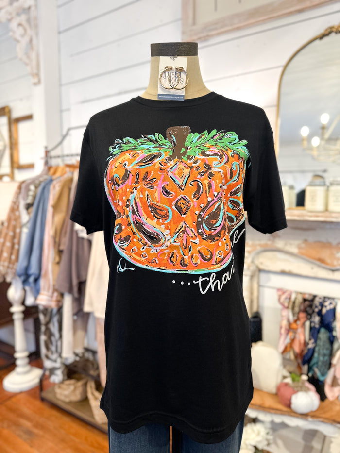 Black t-shirt with a colorful pumpkin design on a mannequin in a store setting.