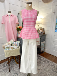 Mannequin wearing a pink checkered top and white pants in a room with decor elements.