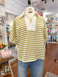Mannequin wearing a yellow/green and white striped shirt with a collar in a store setting.