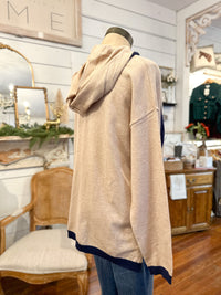 Mannequin wearing a beige hooded jacket in a store setting with Christmas decorations.