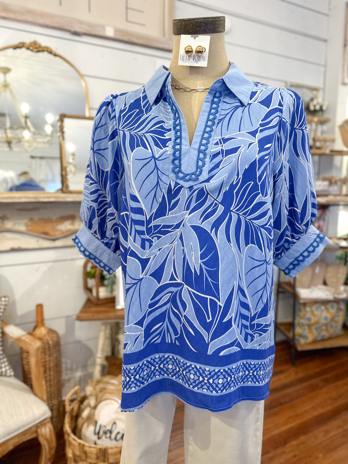 Blue leaf-patterned blouse on a mannequin in a store setting