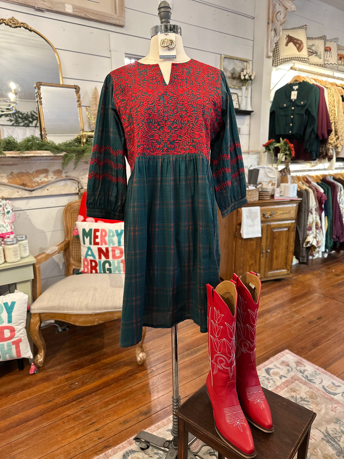 Mannequin wearing a red and green dress with red cowboy boots on a wooden floor.
layerz helen green plaid dress
