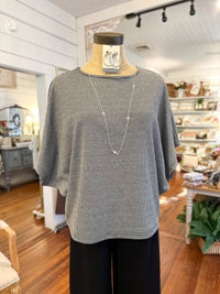 Mannequin wearing a black and white balloon sleeve checkered top and black pants in a store setting