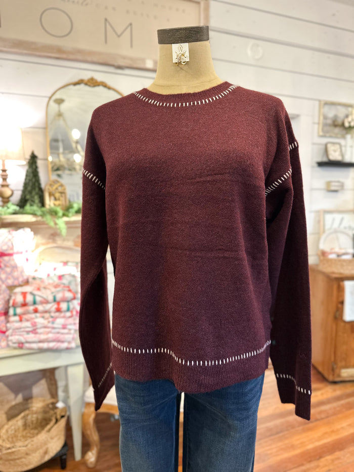 Maroon sweater on a mannequin with a store interior background