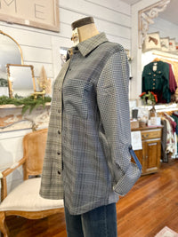 Plaid shirt on a mannequin in a store setting with Christmas decorations.
