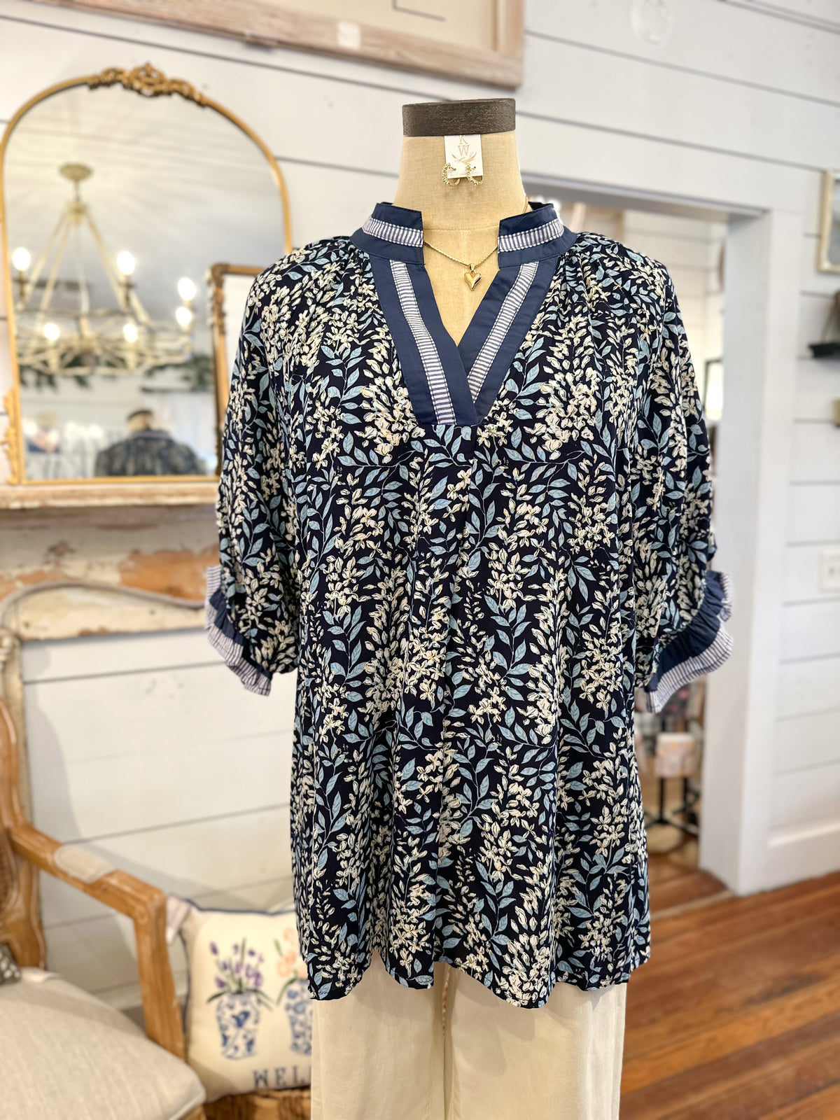 Mannequin wearing a blue and white patterned dress in a room with wooden floor and mirror.