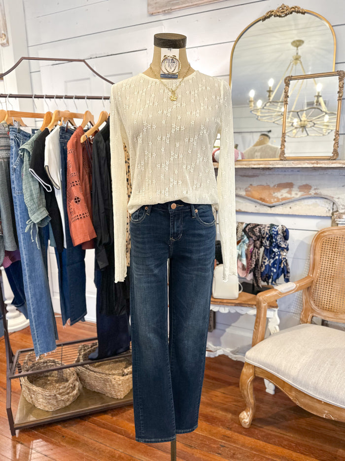 Mannequin wearing a white sweater and blue jeans in a clothing store setting.