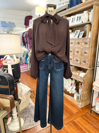 brown long sleeve blouse with bow around neck button down front with dark jeans
