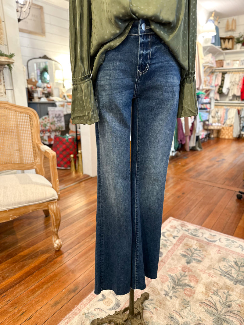 Person wearing a green top and blue jeans on a mannequin in a store 
setting. dear john jaxtyn jean crewe