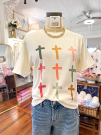 Mannequin wearing a cream t-shirt with colorful cross patterns in a store setting.