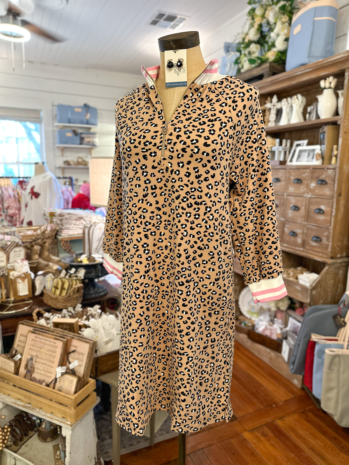 Printed everyday dress with pink accents and zipper on the front inside store setting 