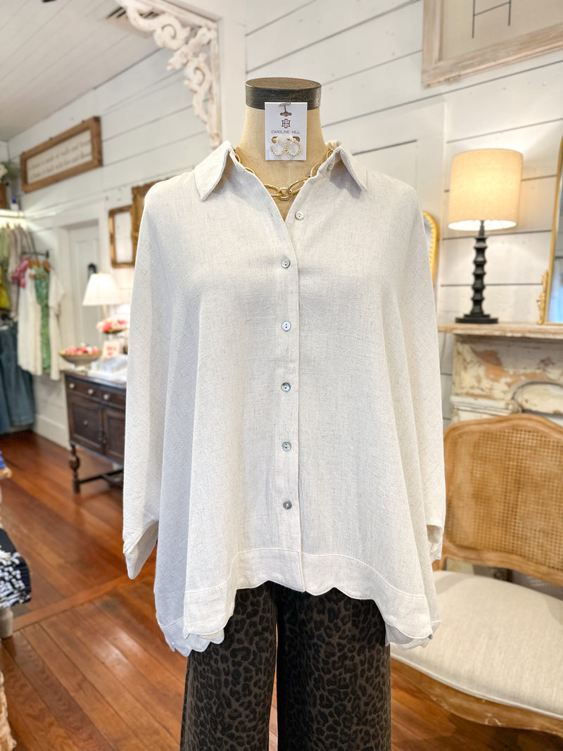 oatmeal linen blend top on a mannequin in a store setting with wooden floor and furniture.