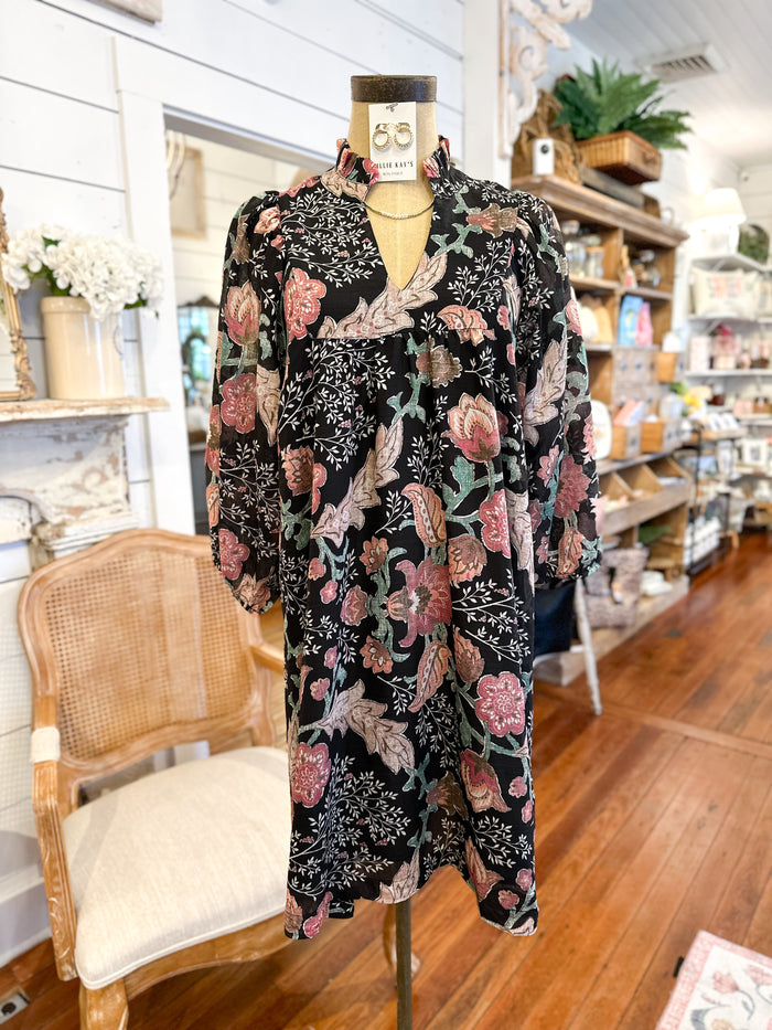 Floral-patterned outfit on a mannequin in a store setting with a chair and shelves in the background.