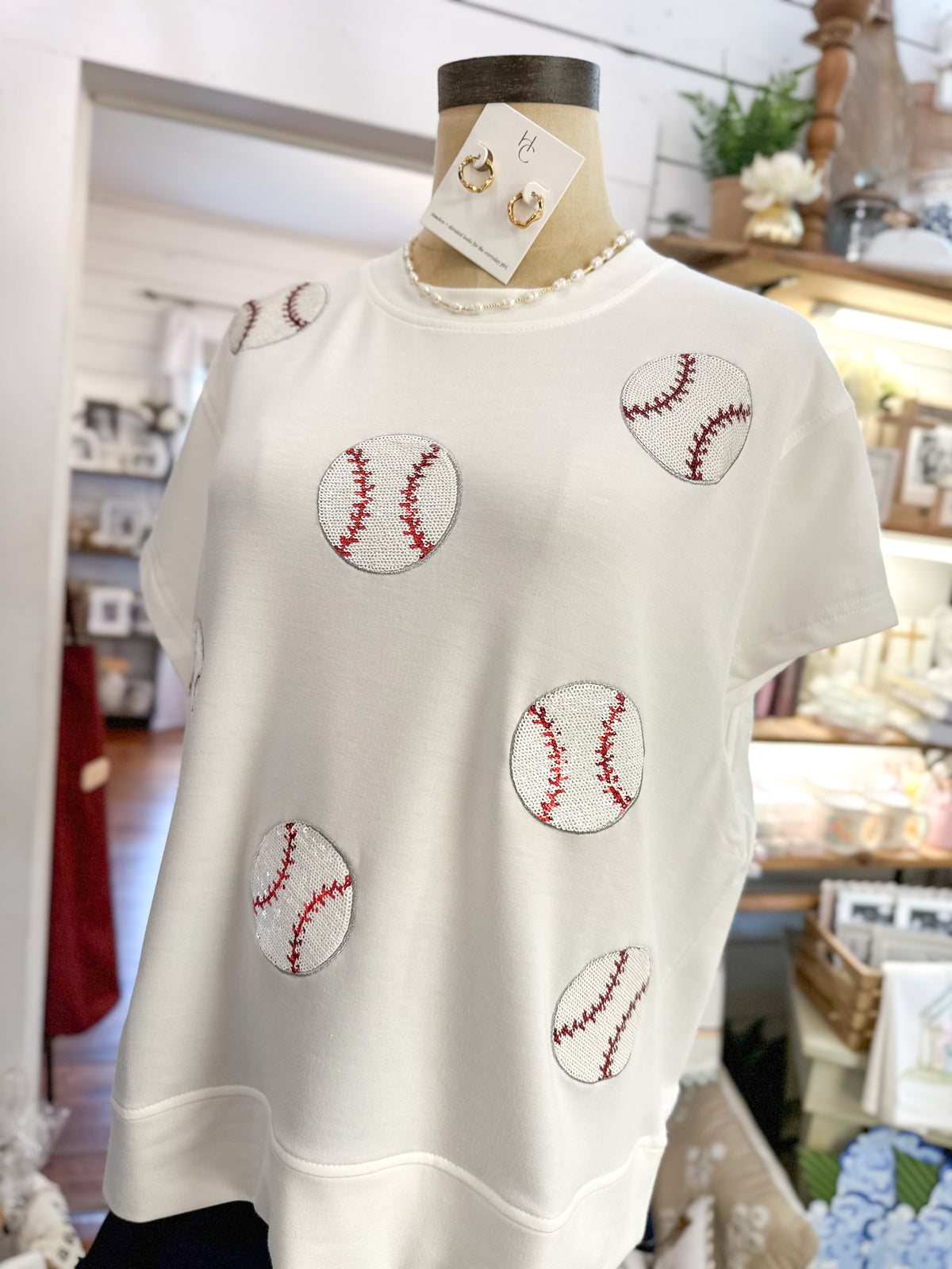 White t-shirt with baseball designs on a mannequin in a store setting