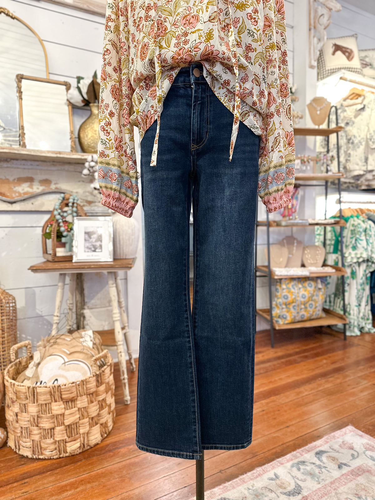 Person wearing a floral top and blue jeans in a store setting dear john annika jean straight leg