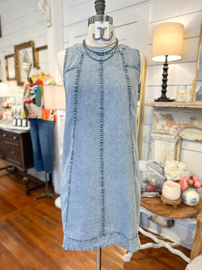 Denim dress on a mannequin in a store setting with various items in the background.