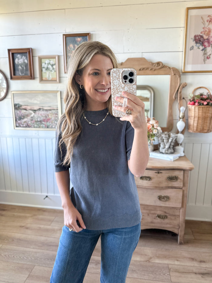 Woman taking a mirror selfie in a room with wooden furniture and decorative items.