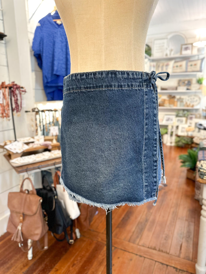 Blue denim skirt on a mannequin in a store setting with various items in the background.