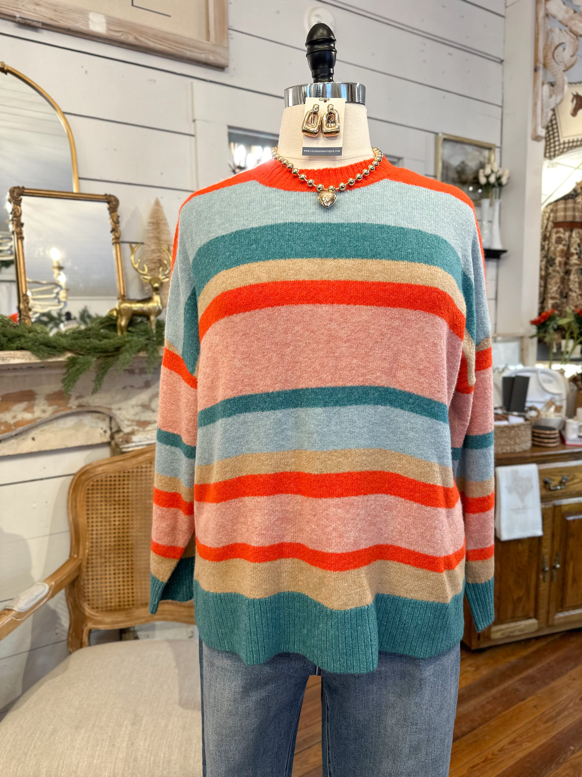 Mannequin wearing a colorful striped sweater in a store setting