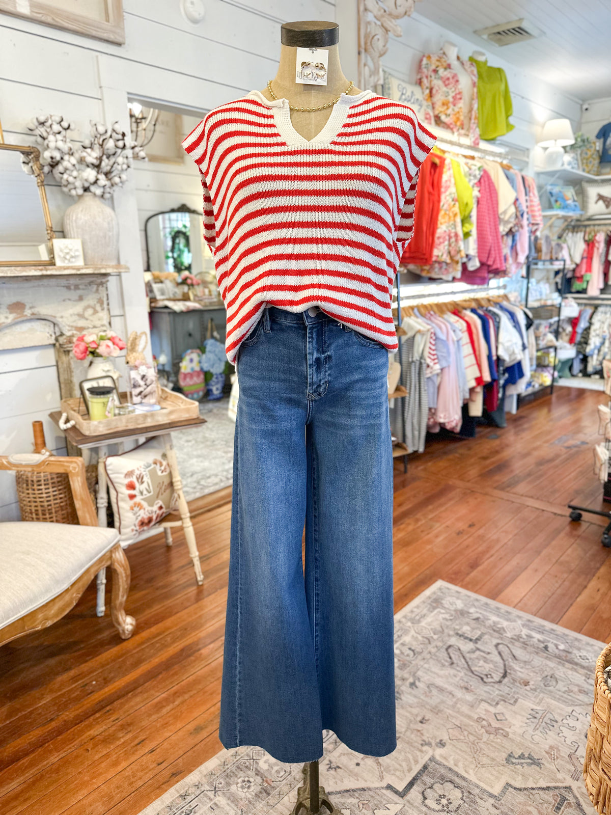Mannequin wearing a red and white striped top and blue jeans in a store setting.