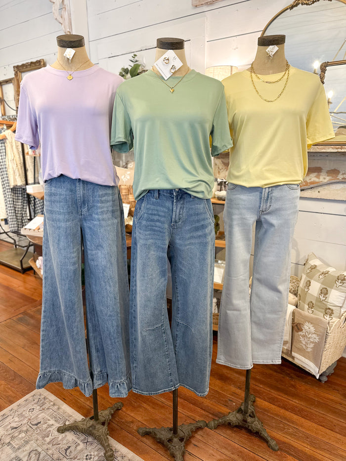 Three mannequins wearing pastel shirts and blue jeans in a store setting.