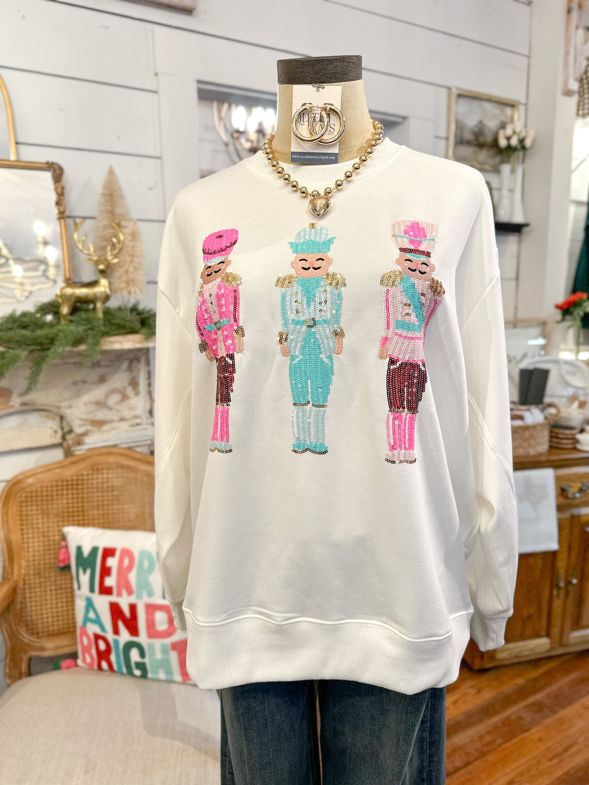 White sweatshirt with colorful nutcracker design on a mannequin in a home setting.