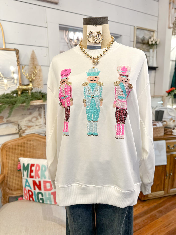 White sweatshirt with colorful nutcracker design on a mannequin in a home setting.