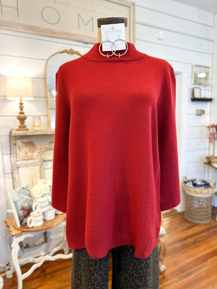 Red sweater on a mannequin in a home setting with decor elements.