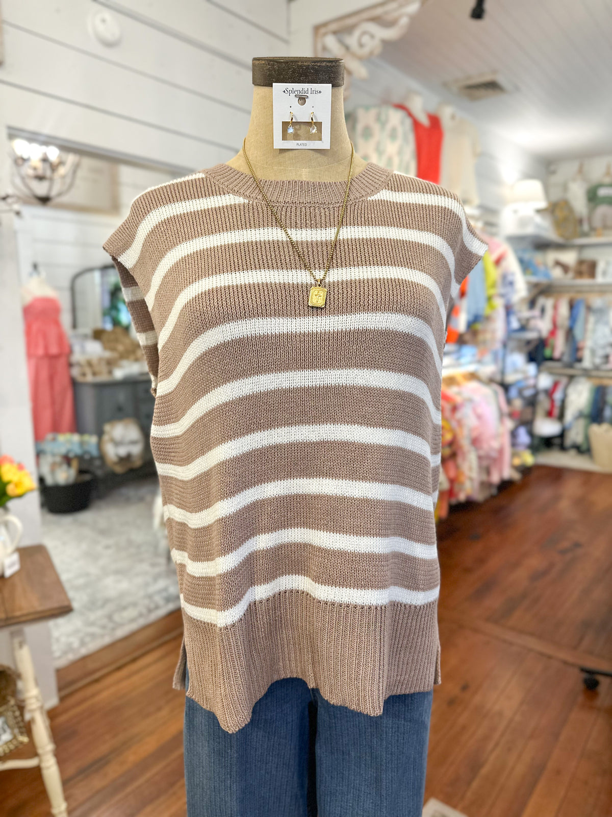 Mannequin wearing a brown and white striped sweater with a store interior background