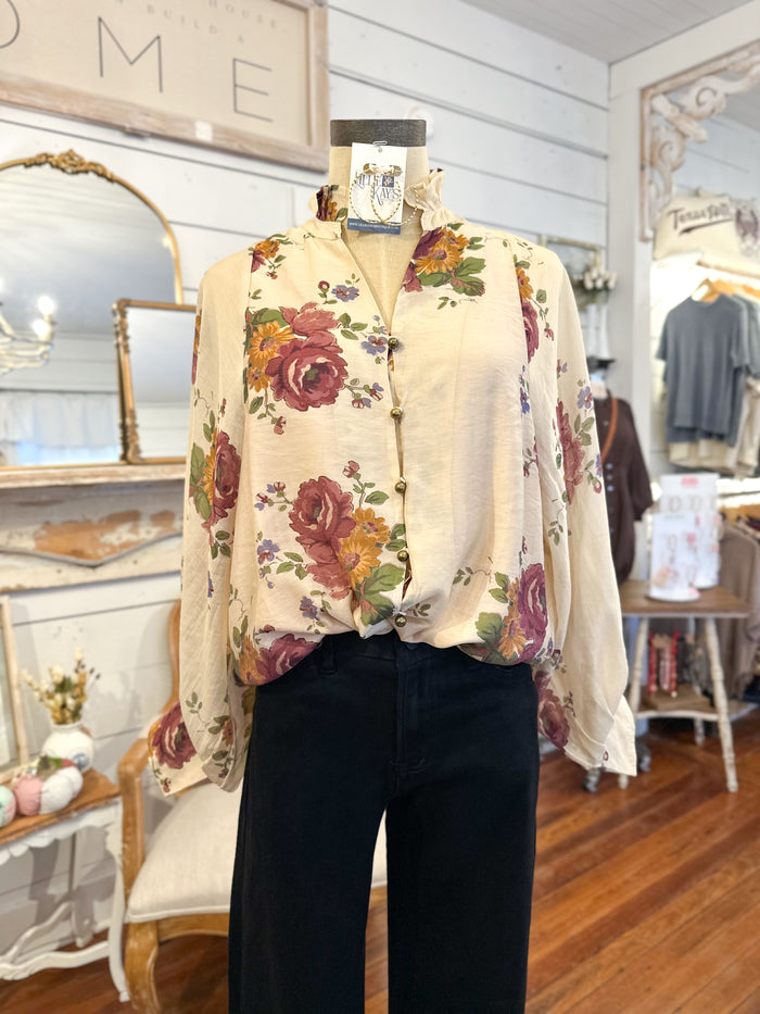 Mannequin wearing a floral blouse and dark pants in a store setting