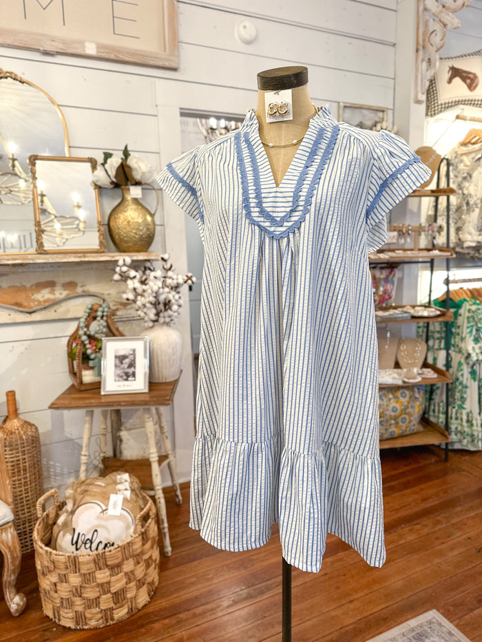 Blue and white striped dress on a mannequin in a store setting with decor items.
