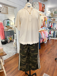 Mannequin wearing a cream blouse and camouflage pants in a store setting