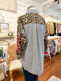 Mannequin wearing a shirt with leopard print sleeves in a store setting
