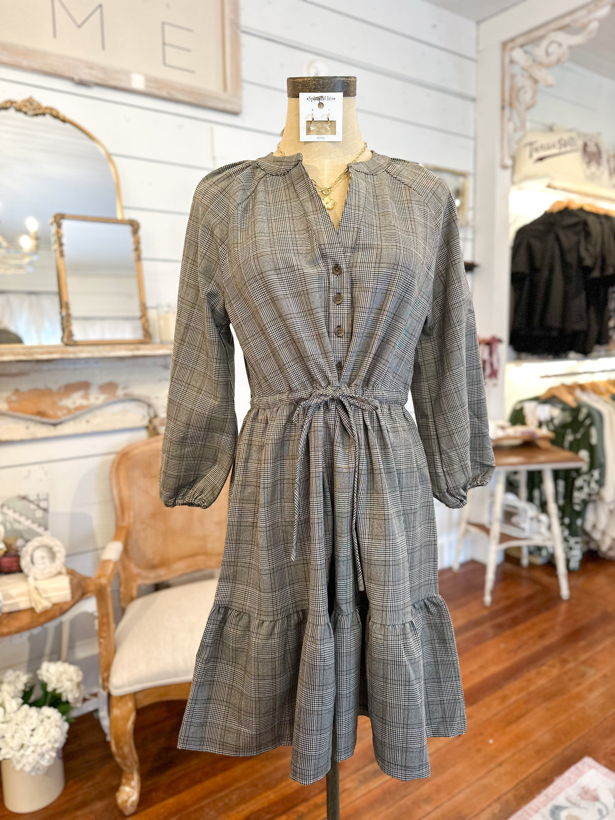 Plaid dress on a mannequin in a store setting with mirrors and furniture.