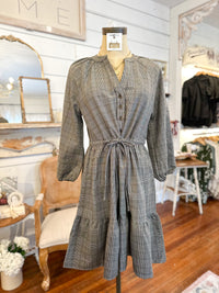 Plaid dress on a mannequin in a store setting with mirrors and furniture.