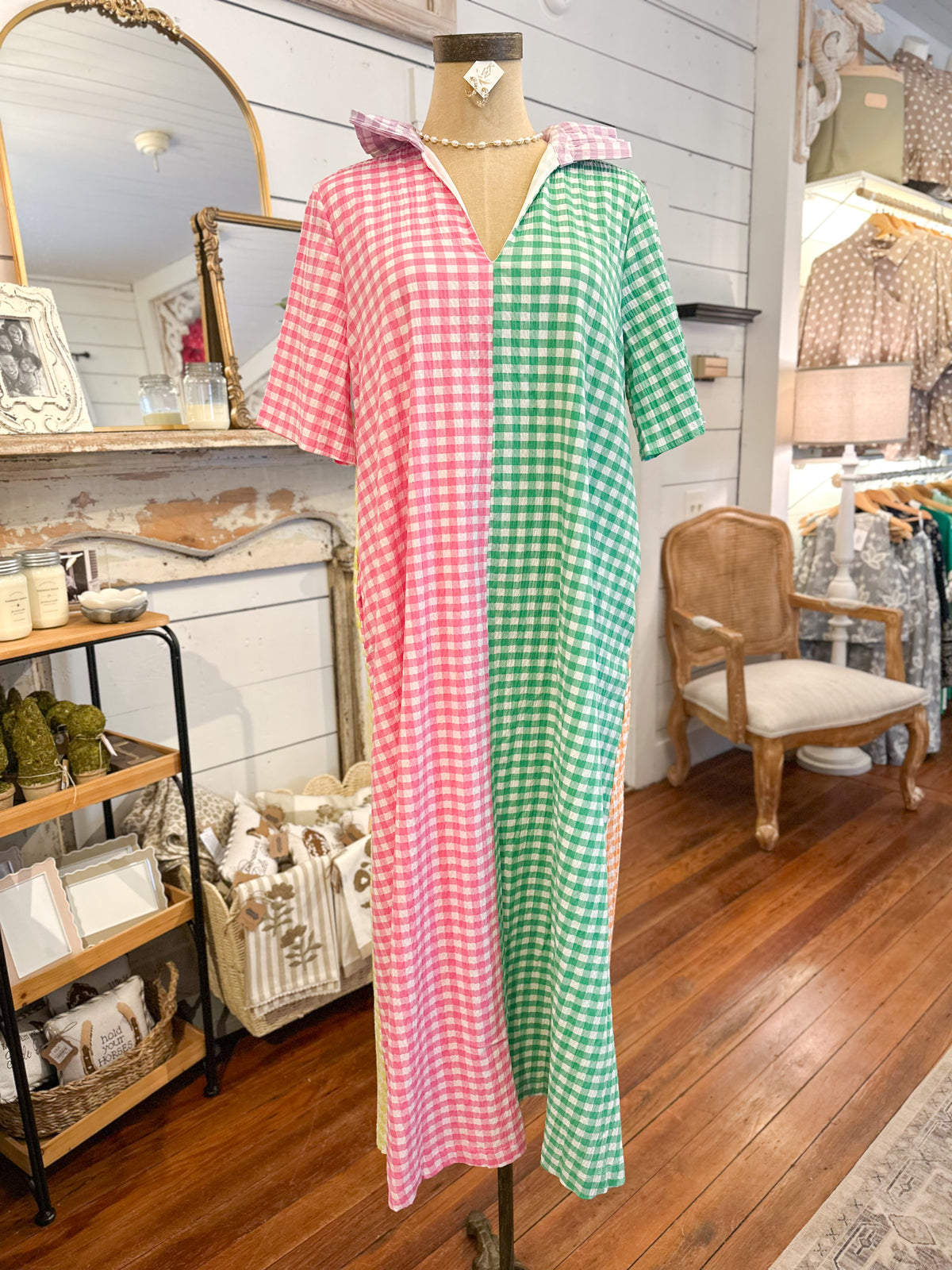 multi color gingham dress on a mannequin in a store setting with wooden floors and shelves.