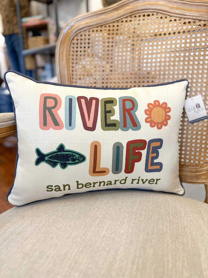 Decorative pillow with 'River Life' text and fish graphic on a chair.
