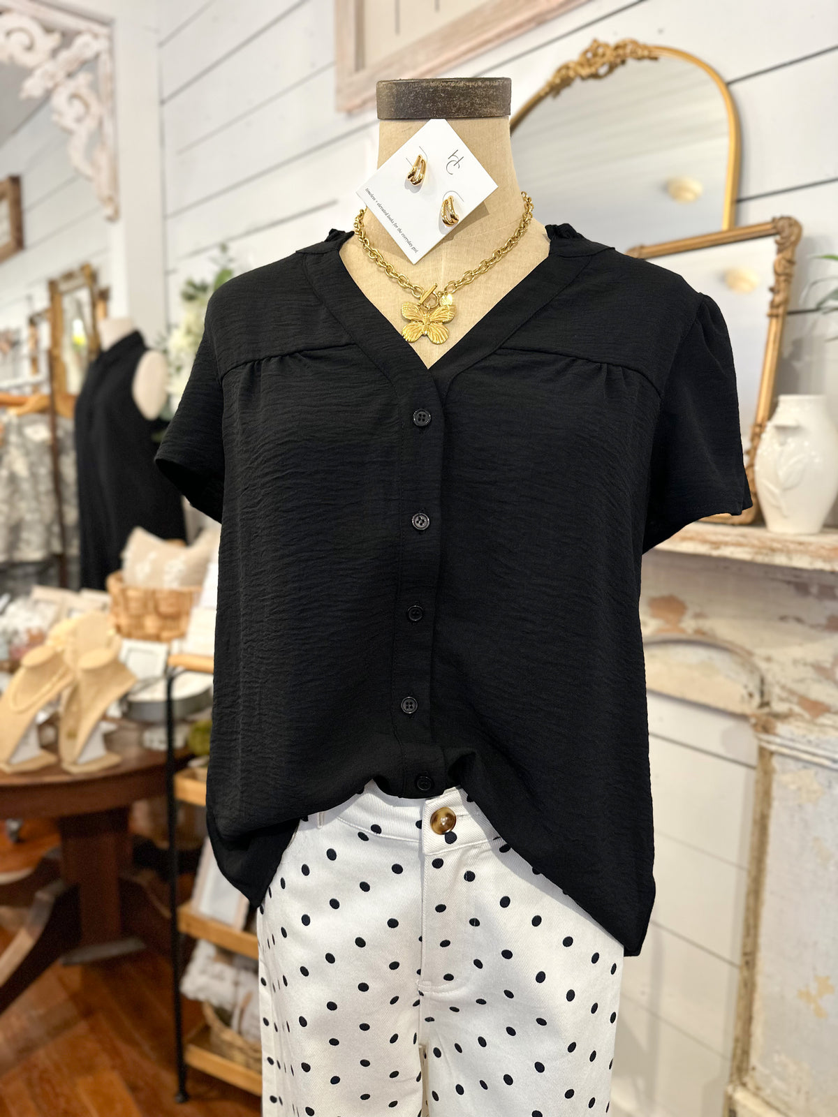 Black blouse on a mannequin with white polka dot pants in a store setting
