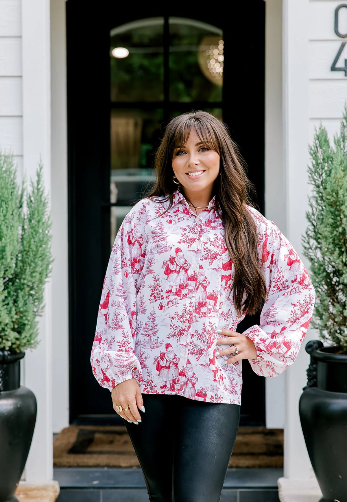 Woman wearing a red santa blouse standing in front of a house entrance.