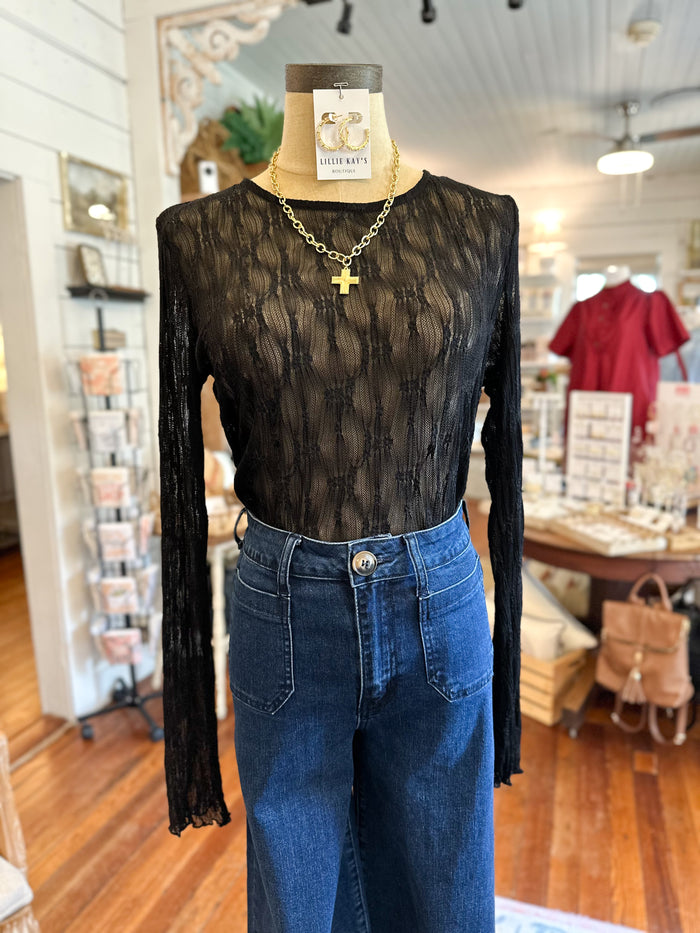 Mannequin wearing a black long-sleeve top and blue jeans in a store setting