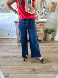 Person wearing a red shirt and blue jeans taking a mirror selfie in a room with wooden flooring and furniture.
MUD PIE JAKE WIDE LEG JEAN 