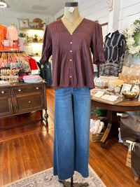 Mannequin wearing a maroon blouse and blue jeans in a store setting