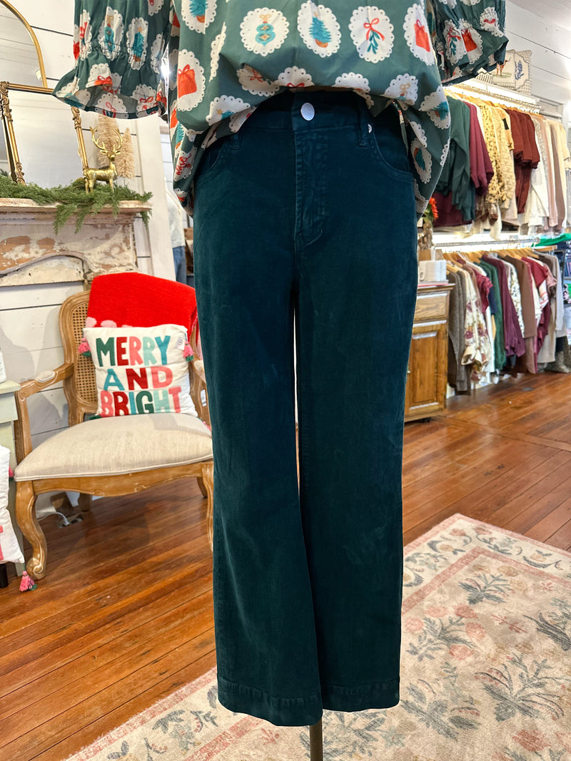 Person wearing teal pants with a patterned top in a store setting