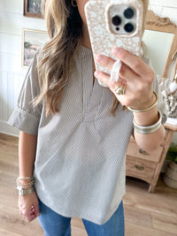 Person wearing a striped shirt and jeans, holding a phone with a textured case.