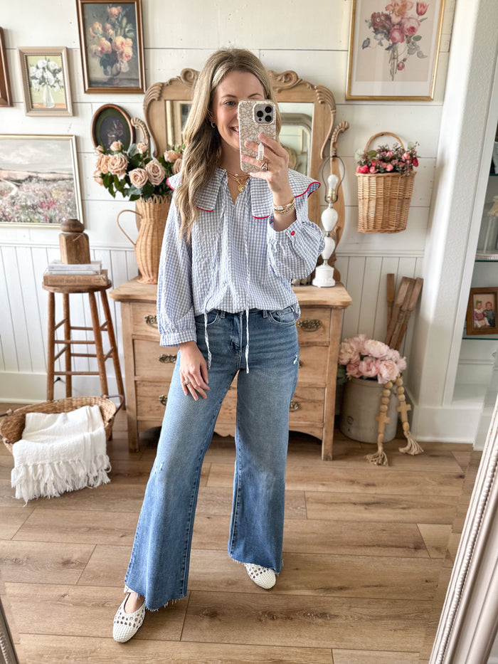 Woman taking a mirror selfie in a room with wooden floors and decor.