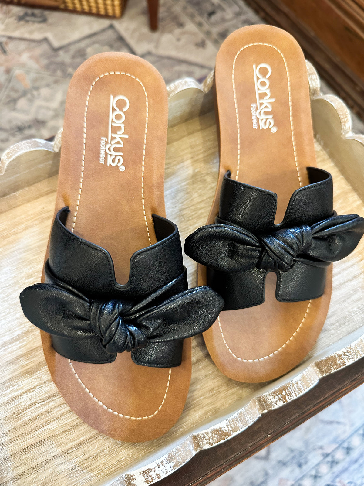 Pair of sandals with black bows on a wooden surface