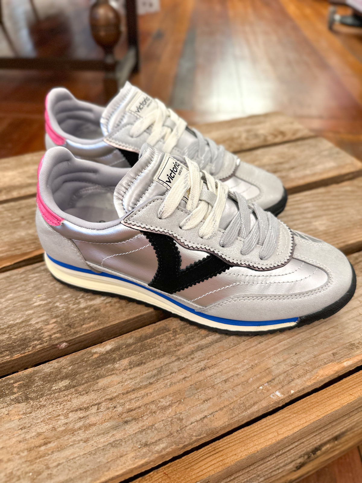 metallic silver sneaker with black V on the side of the sneaker inside store setting 