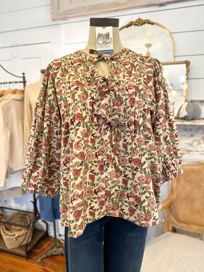 Floral blouse on a mannequin with a tag in a store setting BOWS ON FRONT 
