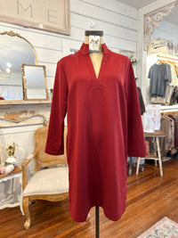 Red dress on a mannequin in a store setting with mirrors and furniture.