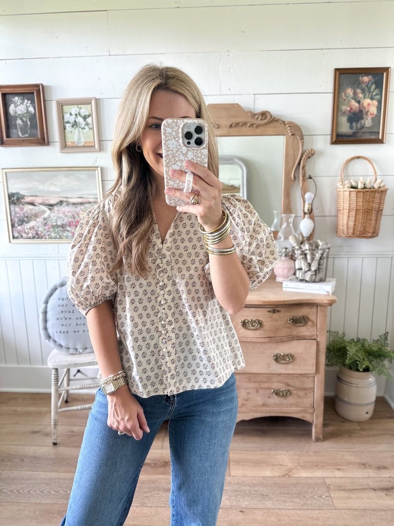 Woman taking a mirror selfie in a room with wooden furniture and decorative items.